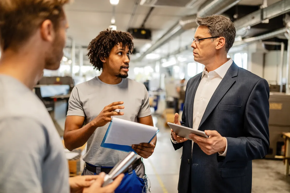 People in a production hall during a business meeting with a recycling machine manufacturer.