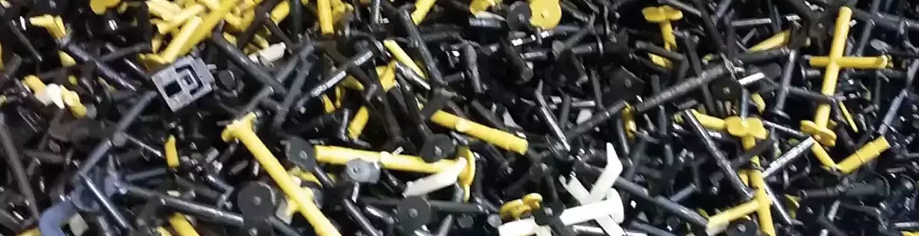 PA Spritzgießteile mit bzw. ohne Glasfasern, in Schwarz, Gelb und Weiß, zum Recyceln befinden sich in einer Kartonbox.